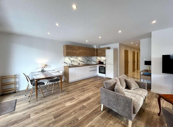 Un apartament modern amb zona de menjador, cuina i saló.