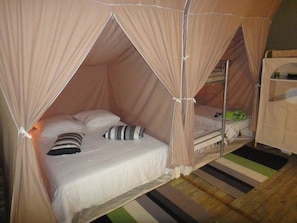 Ein Bett mit Baldachin, ein Nachttisch und eine kleine Ablage mit einem grünen Gegenstand.