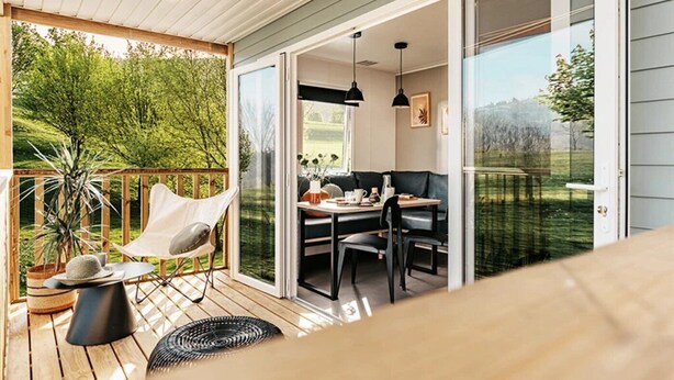 Une terrasse avec une chaise, une table et un pot de fleurs.