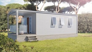 Une maison mobile de plain-pied avec un porche couvert, un petit garage attenant et une cour gazonnée.