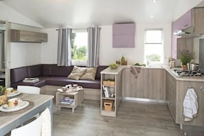 Eine moderne Küche mit eingebautem Herd, ein Essbereich mit Tisch und Stühlen, eine Sitzecke und ein kleiner Couchtisch.