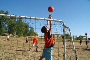 Jogo de futebol em andamento, com jogadores de camisas laranja.