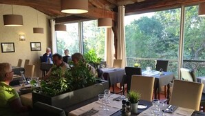 Ein Restaurant mit Außenbereich, gedeckten Tischen und Topfpflanzen.