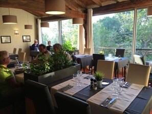 Ein Restaurant mit Außenbereich, gedeckten Tischen und Topfpflanzen.