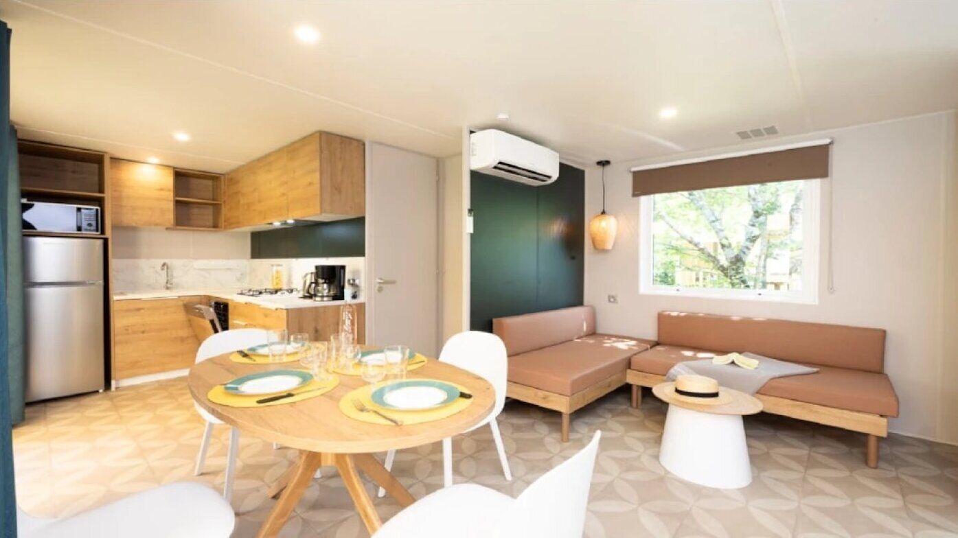 Una cocina compacta con electrodomésticos modernos, un comedor con una mesa redonda y una zona de estar con sofá y una mesita de centro.