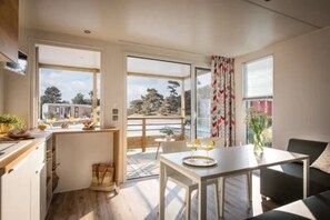 Ein modernes Interieur mit Küche, Essbereich und großen Fenstern, die einen Blick ins Freie ermöglichen.
