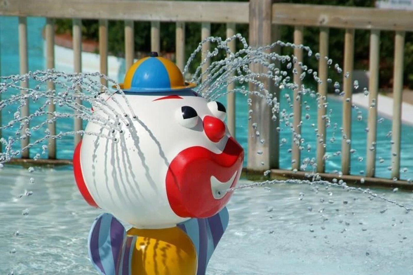 A water feature with a spherical object and a wooden fence in the background.