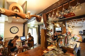 Eine Bar mit Holzzimmermöbeln, einer Wanduhr und verschiedenen Gläsern.