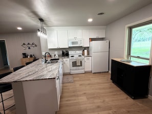 A modern kitchen with white cabinetry, a marble countertop, and a built-in oven.