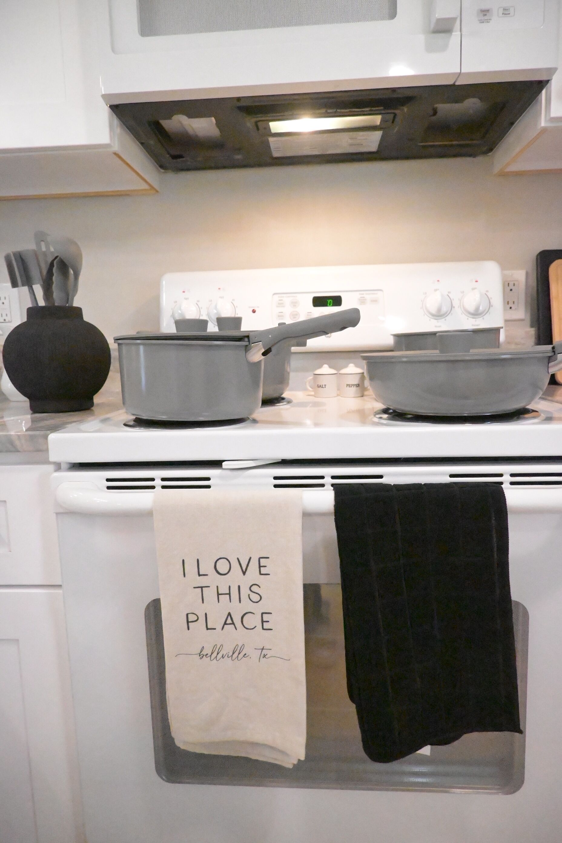 Une cuisine équipée d’une cuisinière, de casseroles et d’un torchon accroché à la porte du four.