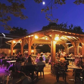 An outdoor dining area with tables and chairs under a wooden pergola. - Camping 4 étoiles - Parc aquatique - ccbfiad (La Romieu)
