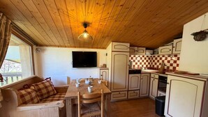 Una cucina compatta con mobili in legno, un tavolo da pranzo e un divano con cuscini a quadretti.