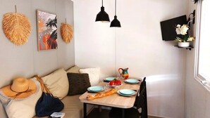 A cozy dining area with a wooden table, black chairs, and a sofa with cushions. - Camping 3 étoiles - Piscine  - ccbfiec (Les Moutiers-en-Retz)