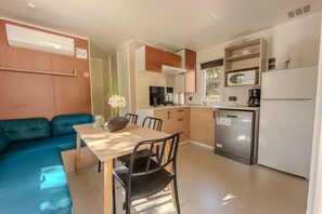 Eine kleine Küche mit Esstisch, Stühlen, einer Sitzecke und einem Kühlschrank.
