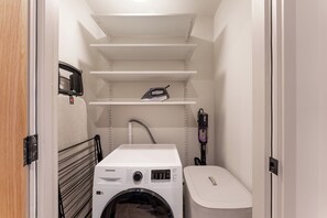 A laundry room with a washing machine, a dryer, and a vacuum cleaner. - Hidden 4- Elvan Duplex Hot Tub (St Ives)