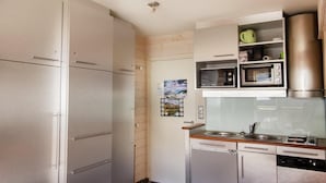 Eine kompakte Küche mit Kühlschrank, Mikrowelle und eingebautem Backofen.