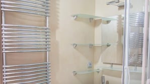 Ein Badezimmer mit Glasdusche, Waschbecken mit blauer Arbeitsplatte und Handtuchhalter.