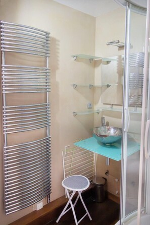 Ein Badezimmer mit Glasdusche, Waschbecken mit blauer Arbeitsplatte und Handtuchhalter.