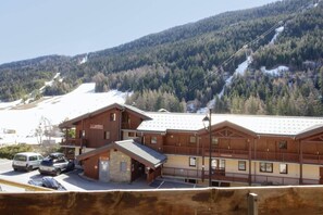 Ein Holzhaus mit Balkon, einem Schild mit der Aufschrift 'Hotel' und einer Skipiste im Hintergrund.