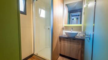 Une salle de bain avec une porte de douche en verre, un meuble-lavabo en bois et un lavabo.