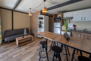 A modern kitchen with a central island, bar stools, a sofa, and a dining table.