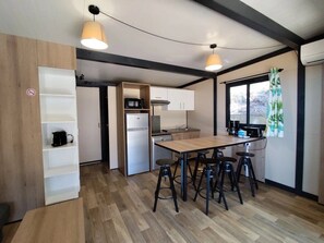 A compact kitchen with a central island, bar stools, and a hanging light fixture.