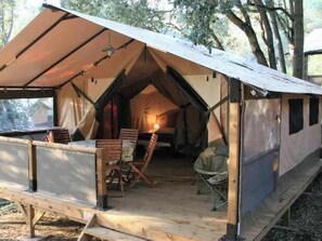 Ein Zelt mit überdachter Veranda, Holzmöbeln und einem kleinen Tisch.