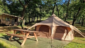 A tent with a picnic table set up on a green tarp in a wooded area. - Camping 3 étoiles - Piscine  - ccbfbcd (Mondragon)