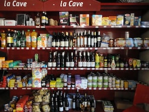 Uma prateleira de loja repleta de diversos produtos alimentícios e bebidas, incluindo garrafas, latas e caixas.