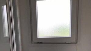 Un baño con ventana, un lavabo blanco y una puerta.
