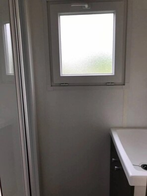 Ein Badezimmer mit Fenster, Waschbecken in Weiß und einer Tür.