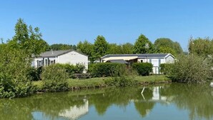 Une propriété située au bord d’un lac, comprenant deux bâtiments blancs, dont l’un possède un porche et l’autre une terrasse couverte.