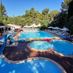 A pool area with multiple swimming pools, lounge chairs, and umbrellas. - Camping 4 étoiles - Piscine  - ccbfibh (Carqueiranne)