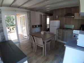 Eine kompakte Küche mit Esstisch, Stühlen, Kühlschrank, Herd und Mikrowelle.