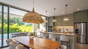 Une cuisine moderne dotée d’un grand îlot central, d’appareils électroménagers en acier inoxydable et d’un coin repas avec une table et des chaises en bois.