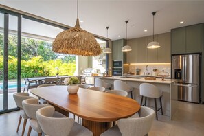 Eine moderne Küche mit einer großen Kochinsel, Edelstahlgeräten und einem Essbereich mit Holztisch und Stühlen.