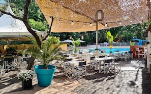 Un espace extérieur aménagé avec des tables et des chaises, une piscine et un coin salon abrité.
