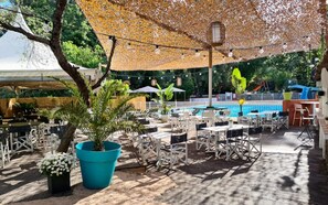 Un espace extérieur aménagé avec des tables et des chaises, une piscine et un coin salon abrité.
