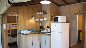 Ett kompakt kök med träväggar, en mikrovågsugn, ett kylskåp och en diskho.