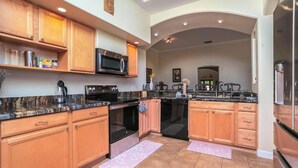A modern kitchen with granite countertops, wooden cabinets, stainless steel appliances, and a central island.