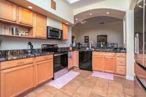 A modern kitchen with granite countertops, wooden cabinets, stainless steel appliances, and a central island. - Nature Oasis Retreat+B&B+Organic Homestead+Sleeps 14+Meditation Space on 2 Acres (Cornville)