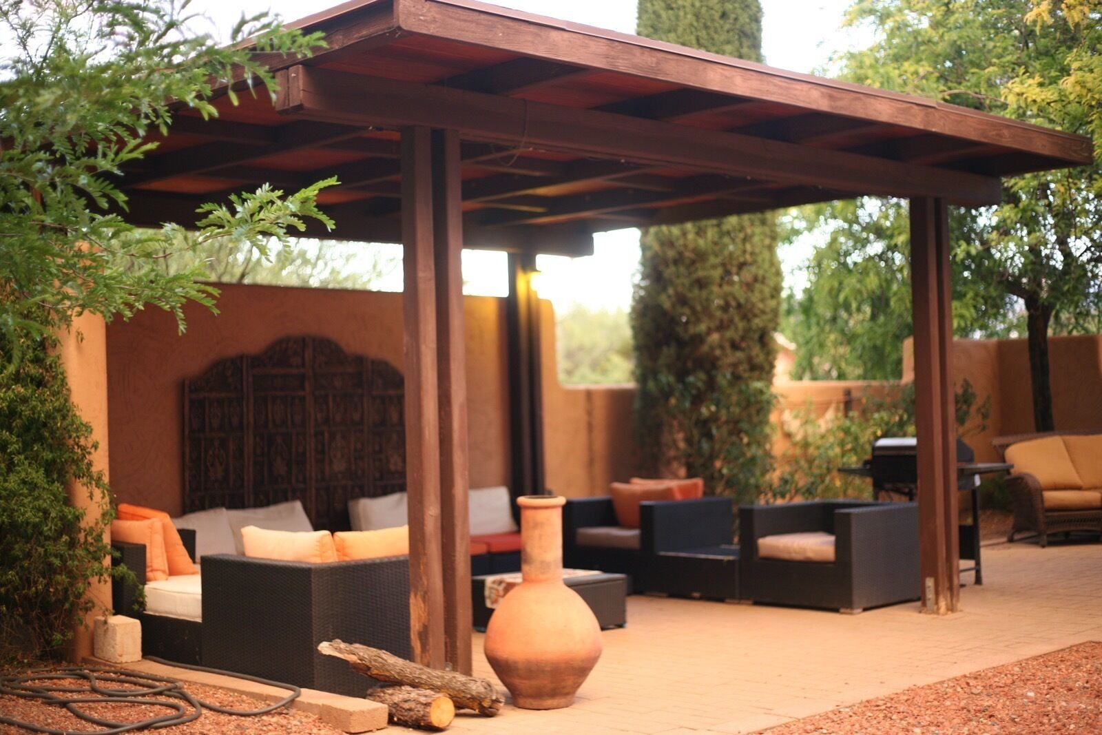 An outdoor seating area with a pergola, sofas, and a large vase.