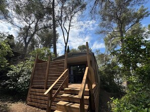 Eine Holzhütte mit einer Treppe, die zu einem Eingang führt, umgeben von Bäumen.