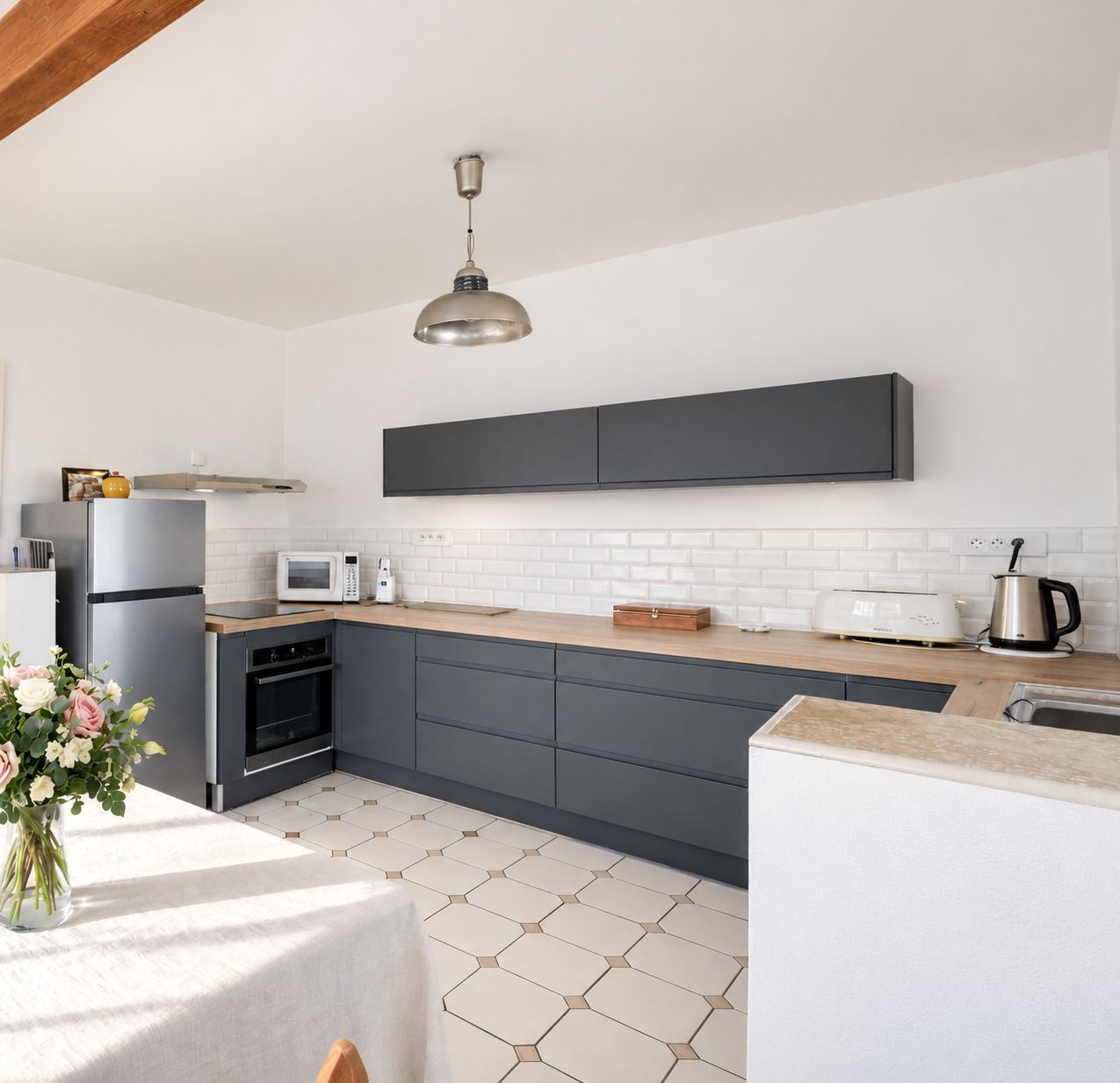 A modern kitchen with a built-in oven, microwave, and a kettle on the countertop.
