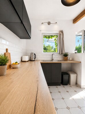 A modern kitchen with a wooden countertop, a window with a view, a sink, and a trash bin. - Le Mas d'Eylieux - Breathtaking view in Ardèche - Gîte Saint Montan (Saint Montan)