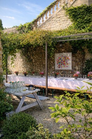 An outdoor dining area with a stone wall, wooden pergola, and a table set for a meal. - Fig Trees · Panoramic View and Pool (Saint Montan)