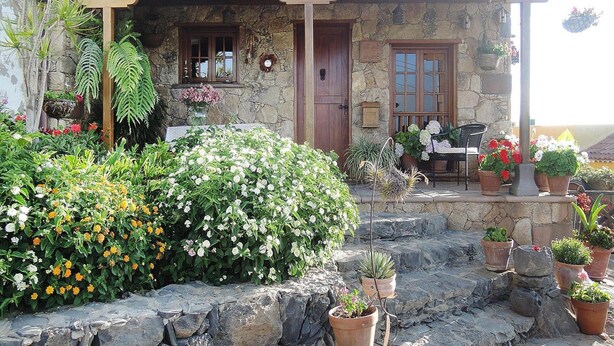 A stone house with a porch, potted plants, and a bench. - Seaview Holiday Home for 4 (Guia de Isora)