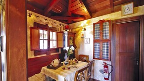 A cozy room with a wooden table, chairs, a bed, and a fire extinguisher. - Seaview Holiday Home for 4 (Guia de Isora)
