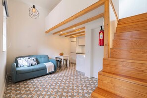 Un interno moderno con un pavimento a motivi geometrici, un divano blu, una scala in legno e una zona cucina.