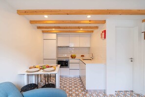 Una cucina compatta con mobili bianchi, un forno a microonde e un tavolo con sedie.